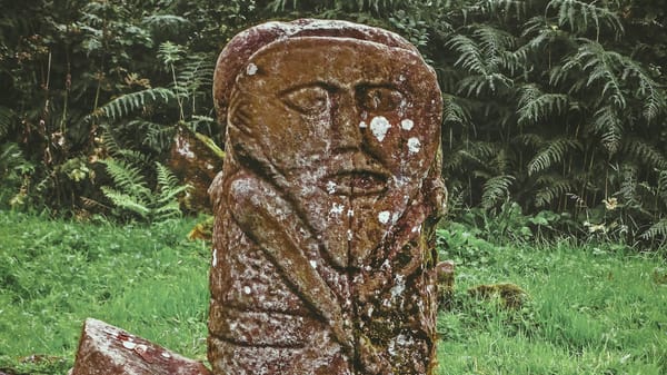 A statue of Janus, the god of duality, transitions and beginnings, in a forest.