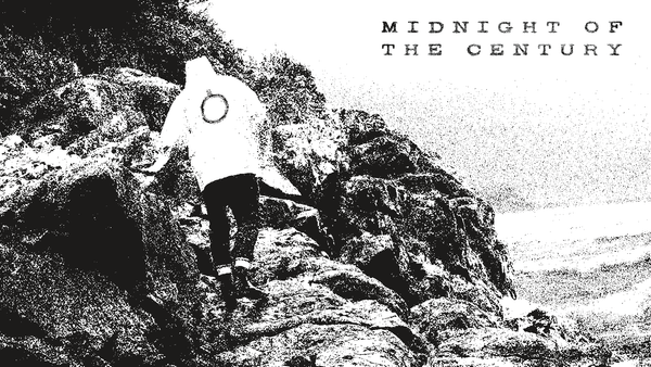 Moody black and white image of a person scrambling over a rocky coastline